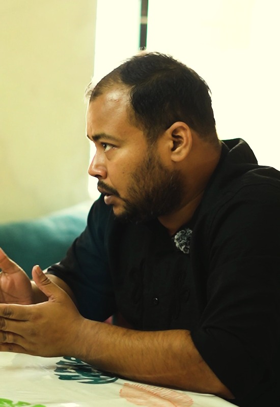 K M Shamir Azam Saikat speaking at a table, a pack of Chumuk beside him